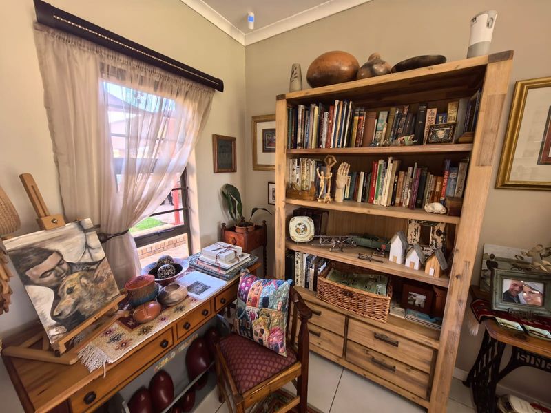 A cozy room featuring tiled flooring and cove cornicing, currently utilized as a study or hobby space with natural light from the window.