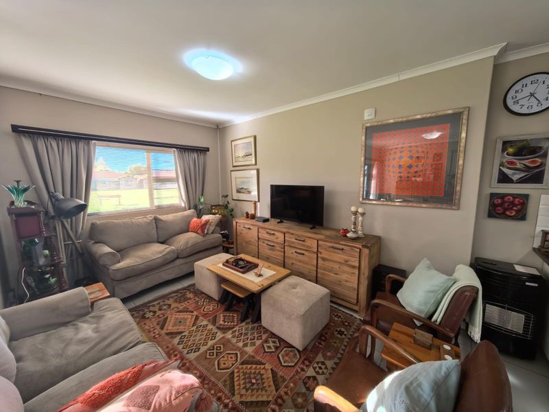 A comfortable living room featuring neutral wall tones, a large window with curtain tracks, and standard ceiling finishes.