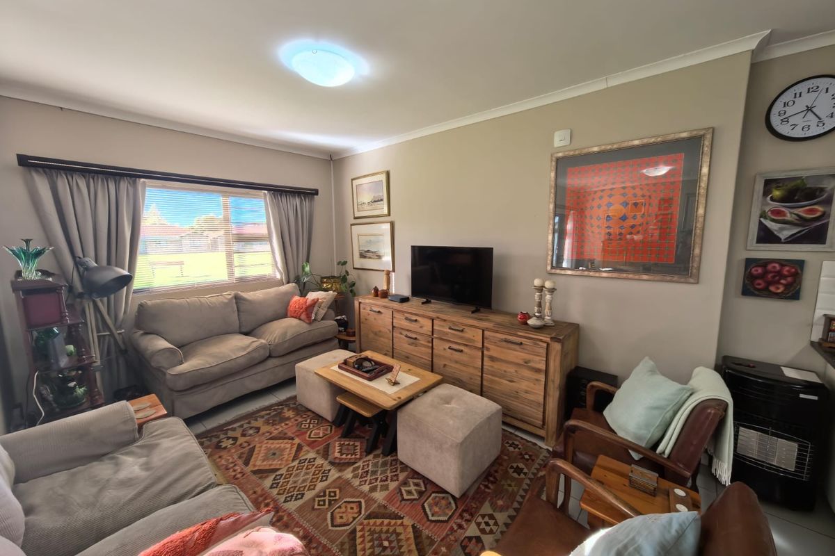 A comfortable living room featuring neutral wall tones, a large window with curtain tracks, and standard ceiling finishes.