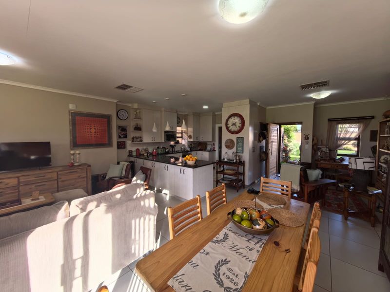 Spacious open-plan living, dining, and kitchen area featuring tiled floors, a central kitchen island with granite countertops, and integrated cabinetry.