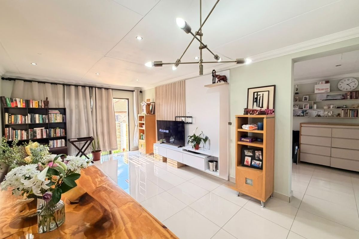 Spacious living room featuring polished tile flooring, modern lighting, and a custom built-in media wall with decorative slatted paneling.
