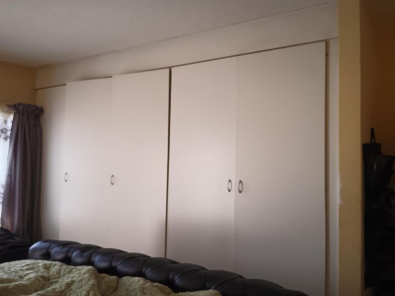 A bedroom featuring extensive floor-to-ceiling built-in cupboards providing ample storage space.