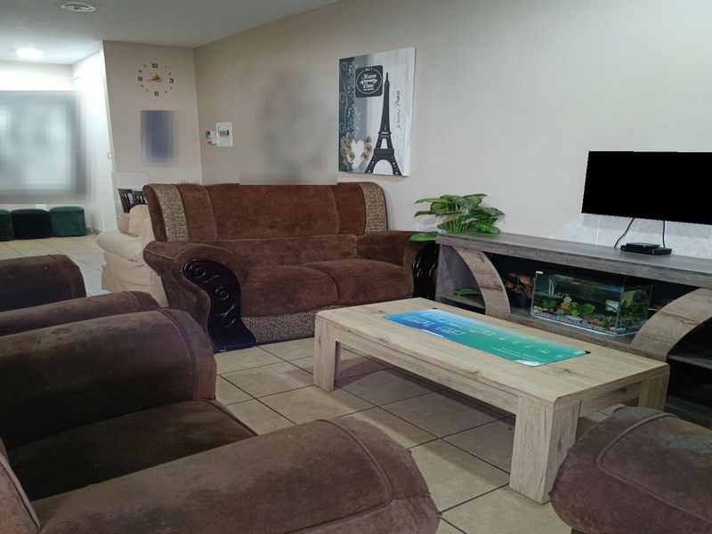 A functional living room area featuring neutral wall tones and ceramic floor tiling, providing a comfortable space for relaxation.