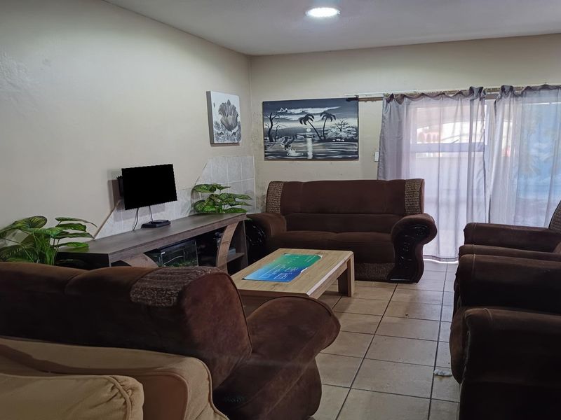 A functional living room featuring tiled flooring, recessed ceiling lights, and a sliding glass door providing access to the exterior.