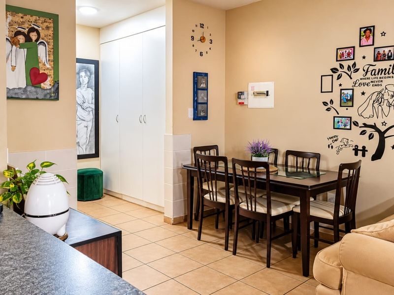 Open plan living and dining area featuring tiled flooring and built-in storage cupboards, creating a functional and connected space.