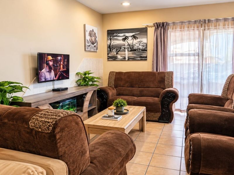A comfortable living room featuring tiled flooring, recessed lighting, and a sliding glass door providing access to the exterior.
