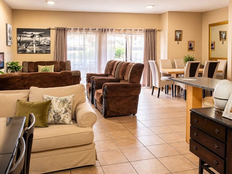 Spacious open-plan living and dining area featuring tiled flooring, recessed lighting, and sliding glass doors leading to an outdoor space.