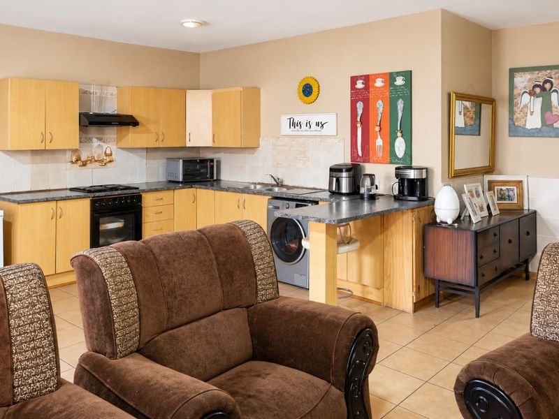 Open plan kitchen and living area featuring light wood cabinetry, laminate countertops, and tiled flooring, offering a functional and connected living space.
