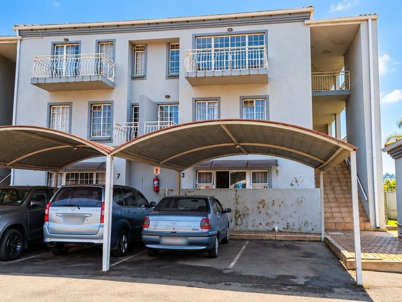 Front elevation of a multi-story apartment complex featuring covered parking bays, private balconies, and external stair access.