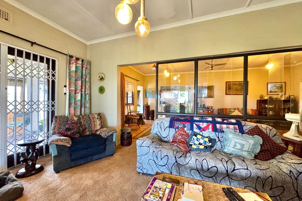 A living room featuring a glass partition wall, security gate access to the exterior, and carpeted flooring.