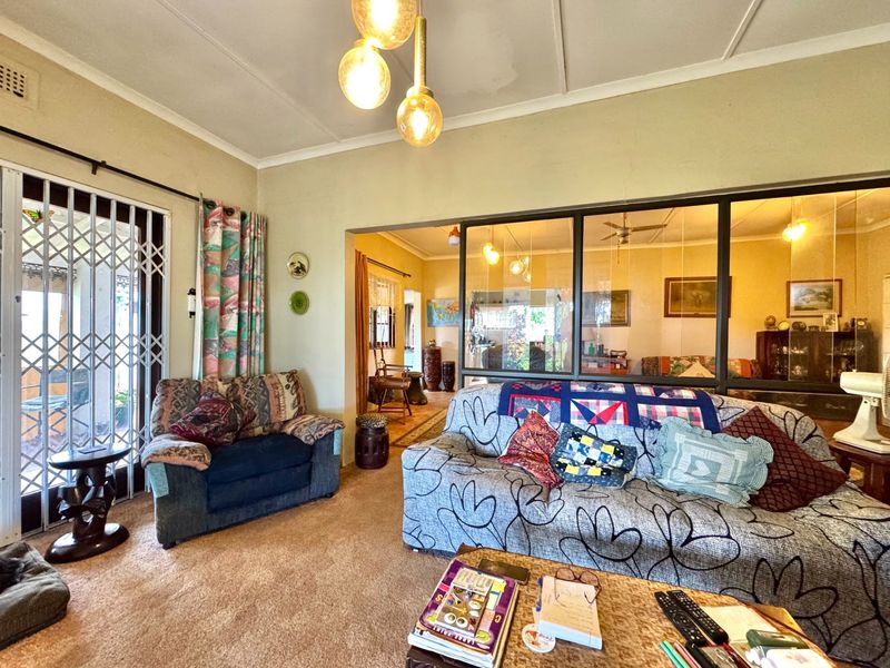 A living room featuring a glass partition wall, security gate access to the exterior, and carpeted flooring.