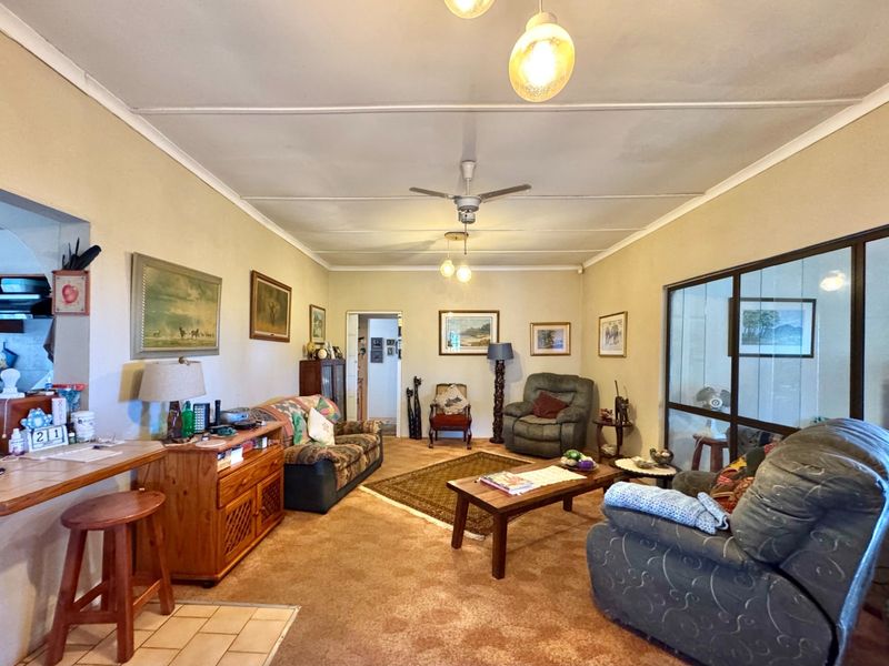 Spacious living room featuring a breakfast bar, ceiling fan, and a sliding glass partition, offering a functional layout with potential for modern updates.