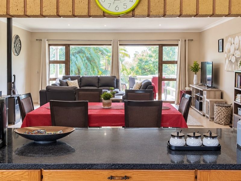 Spacious open-plan living and dining area featuring a granite kitchen island, wood-burning fireplace, and large sliding doors leading to an outdoor space.
