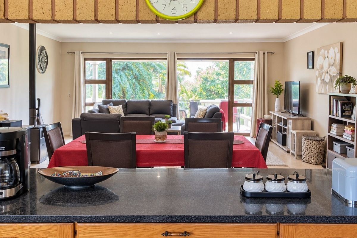 Spacious open-plan living and dining area featuring a granite kitchen island, wood-burning fireplace, and large sliding doors leading to an outdoor space.