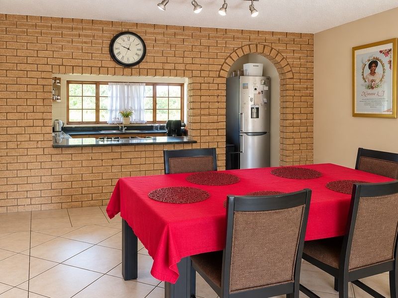 Open-plan dining area featuring an exposed brick feature wall with an arched alcove and a convenient pass-through window to the kitchen.