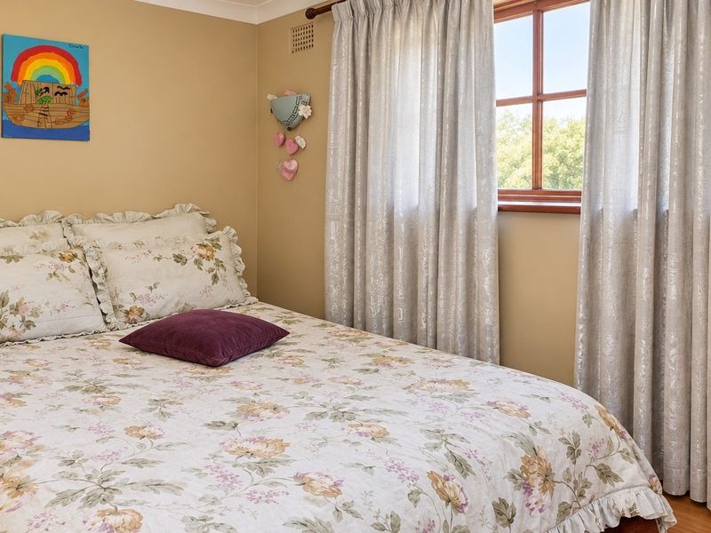 A cozy bedroom featuring neutral wall tones, timber-framed windows, and natural light, providing a comfortable and functional sleeping space.