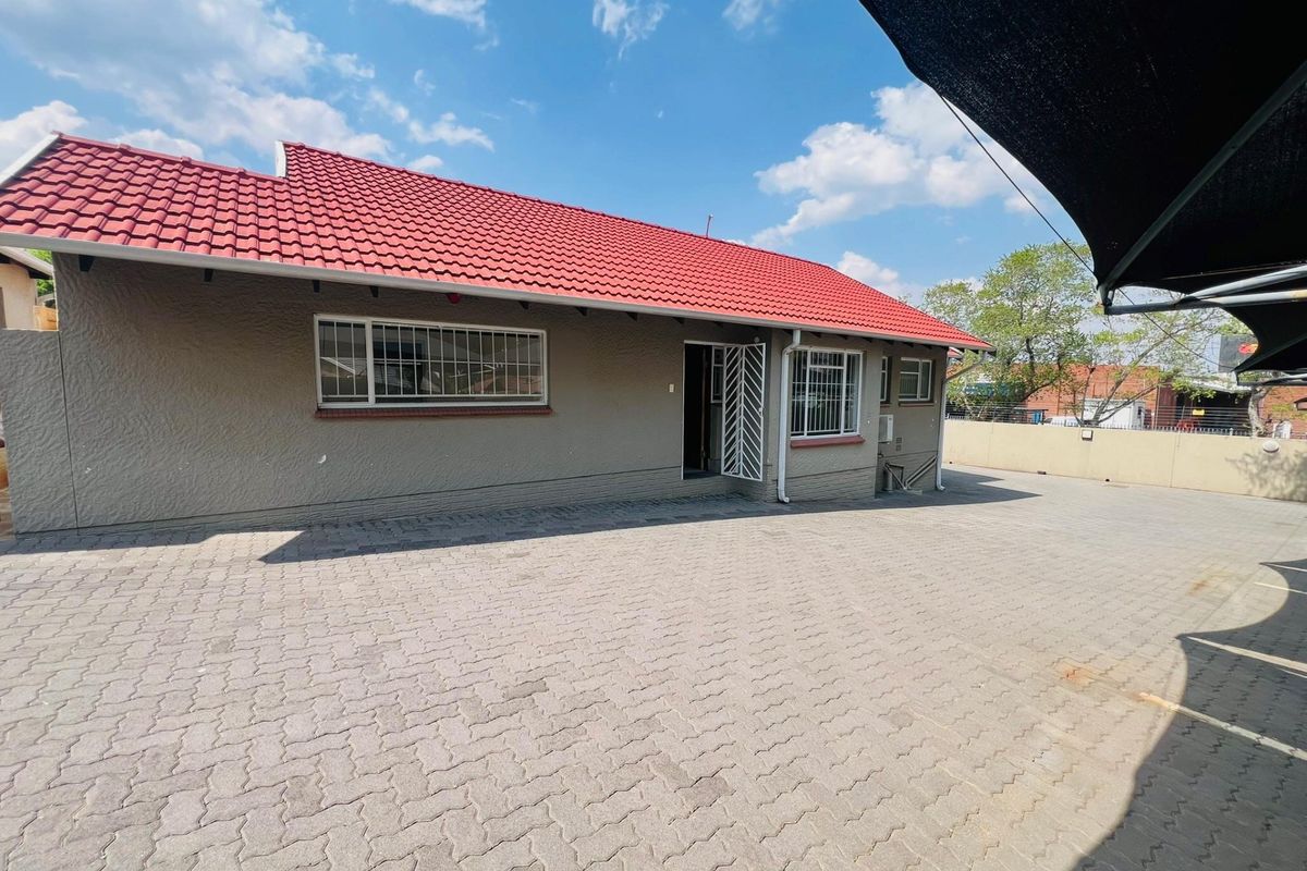 Rear exterior view of the commercial property featuring a paved courtyard, secure entrance, and a well-maintained tiled roof.