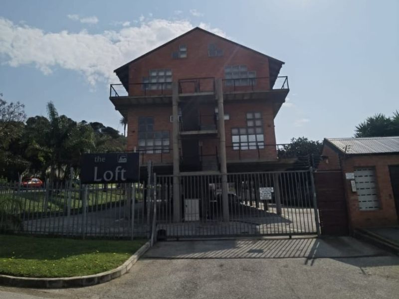 Front exterior view of The Loft apartment building featuring a brick facade, metal security gate, and external balcony access.