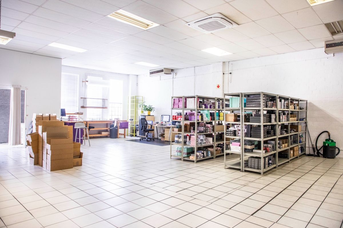 A spacious commercial utility or storage area featuring tiled flooring, suspended ceilings, and integrated air conditioning units.