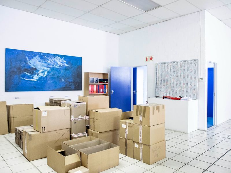 A functional commercial office space featuring a suspended ceiling, tiled flooring, and a built-in service counter, currently utilized for storage.