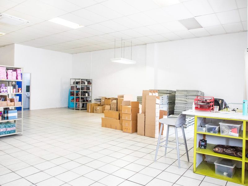 A functional commercial utility or storage space featuring durable ceramic floor tiles, a suspended ceiling with recessed lighting, and integrated air conditioning.