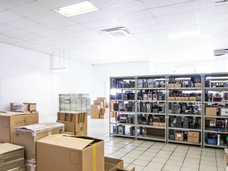 A functional commercial utility or storage space featuring durable ceramic floor tiles, a suspended ceiling with recessed lighting, and a ceiling-mounted air conditioning unit.
