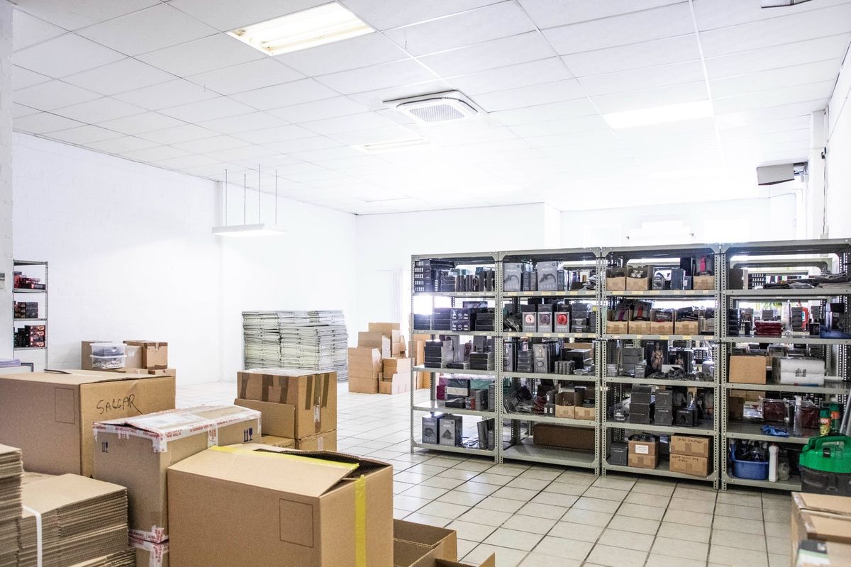 A functional commercial utility or storage space featuring durable ceramic floor tiles, a suspended ceiling with recessed lighting, and a ceiling-mounted air conditioning unit.