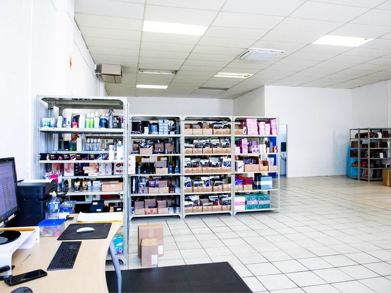 A functional commercial utility or storage space featuring tiled flooring, a suspended ceiling with recessed lighting, and integrated air conditioning.