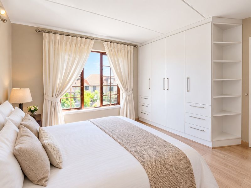 A well-maintained bedroom featuring light laminate flooring and extensive white built-in cabinetry with integrated shelving.