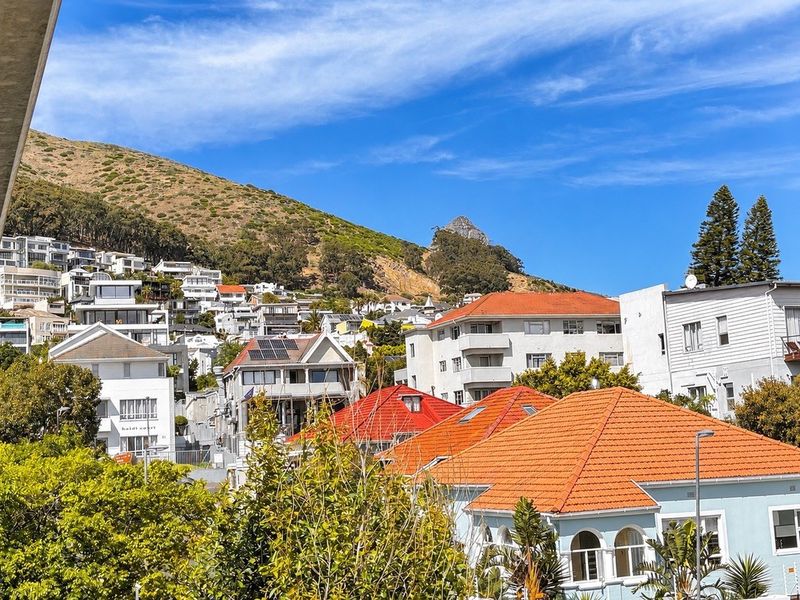 An elevated view overlooking a residential neighbourhood with hillside scenery and mountain backdrop.