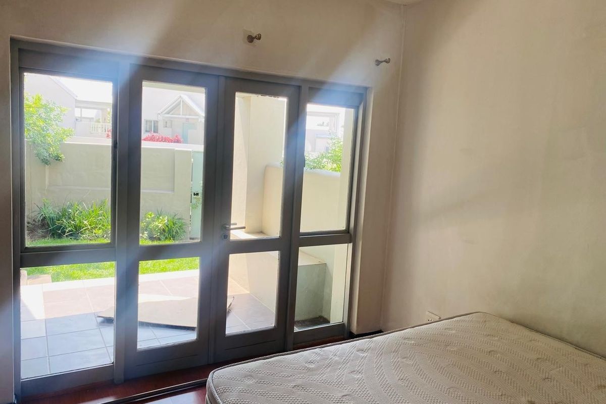 Bedroom featuring laminate flooring and large aluminium-framed glass doors providing direct access to an outdoor patio area.
