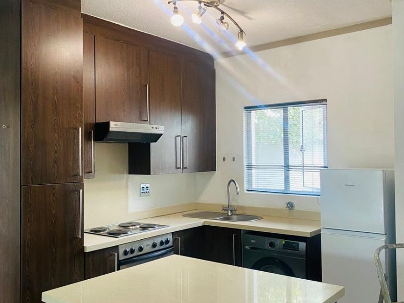 A functional kitchen featuring dark wood cabinetry, stone countertops, integrated appliances, and a central island, providing efficient workspace and storage.