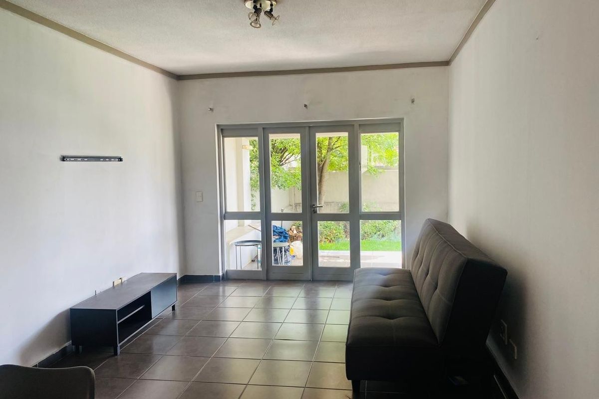 A living room featuring tiled flooring and large glass doors providing access to an outdoor area, offering a bright and functional living space.