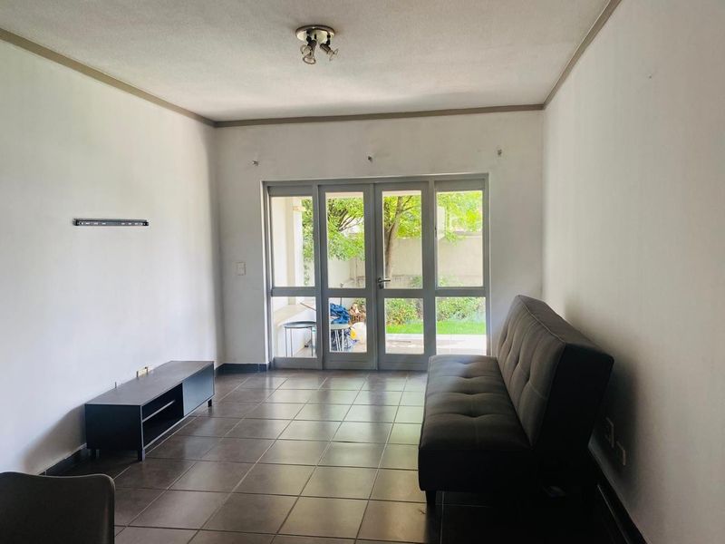 A living room featuring tiled flooring and large glass doors providing access to an outdoor area, offering a bright and functional living space.