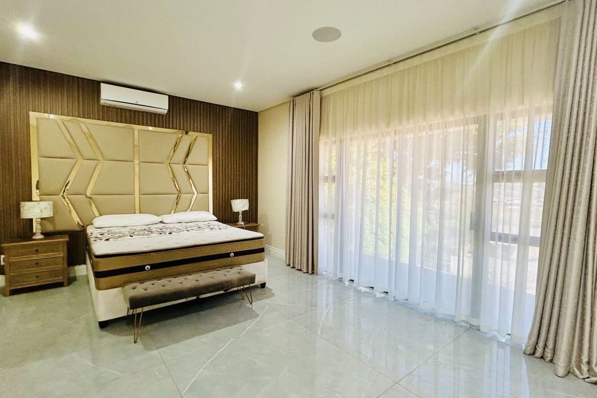 Spacious bedroom featuring a wood panel accent wall, large sliding glass doors with floor-to-ceiling curtains, tiled flooring, and integrated air conditioning.