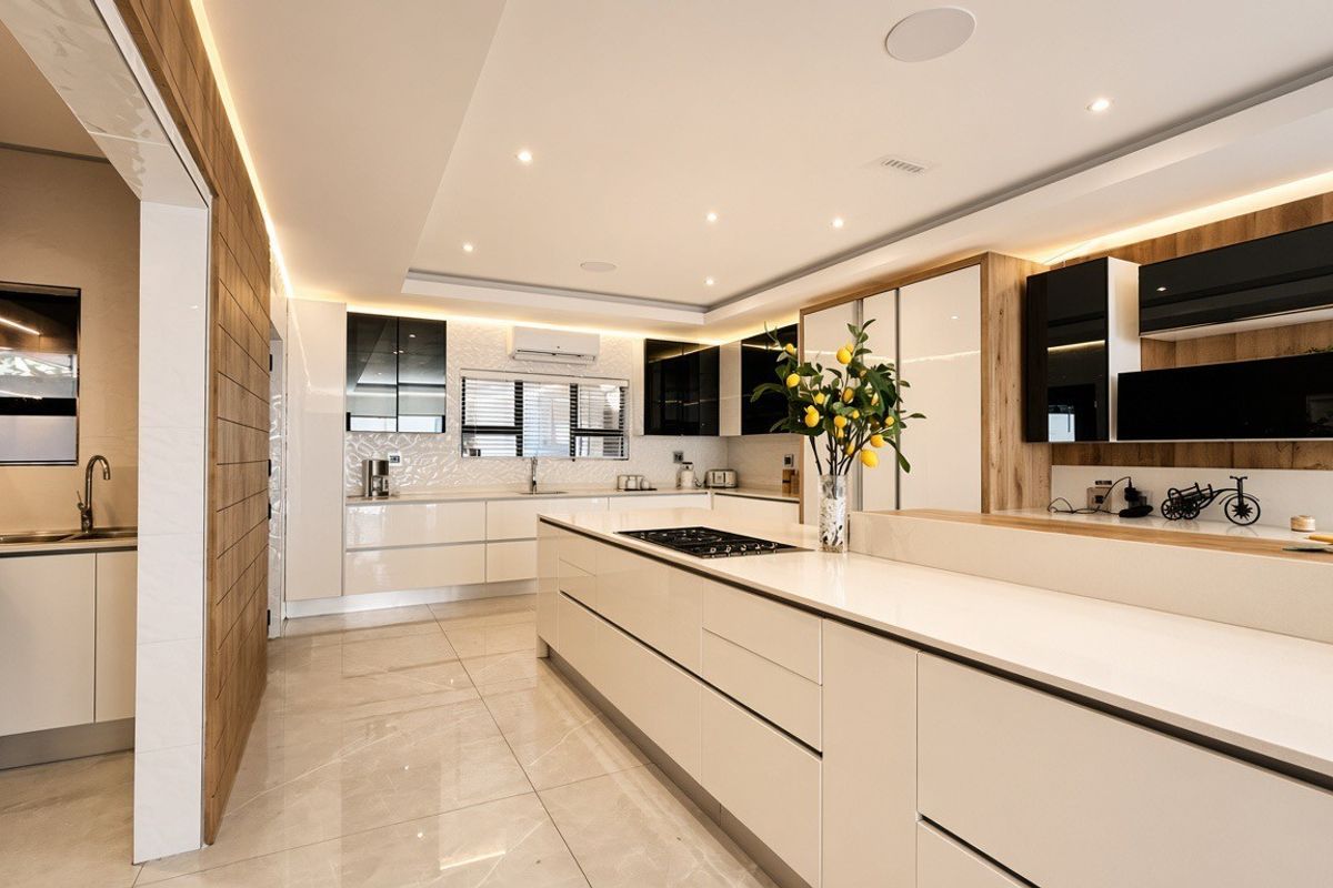 Modern, high-end kitchen featuring a large central island, sleek cabinetry, stone countertops, and integrated appliances with recessed lighting and polished tile floors.