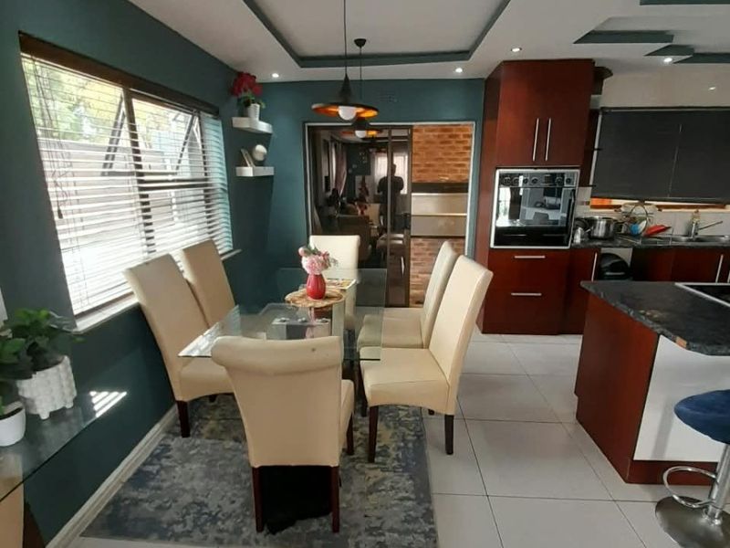 Open-plan dining and kitchen area featuring modern cabinetry, a built-in oven, kitchen island, and tiled flooring with recessed ceiling lighting.