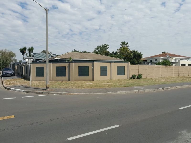 Street view of the property showing the perimeter wall, tiled roof, and surrounding pavement area.