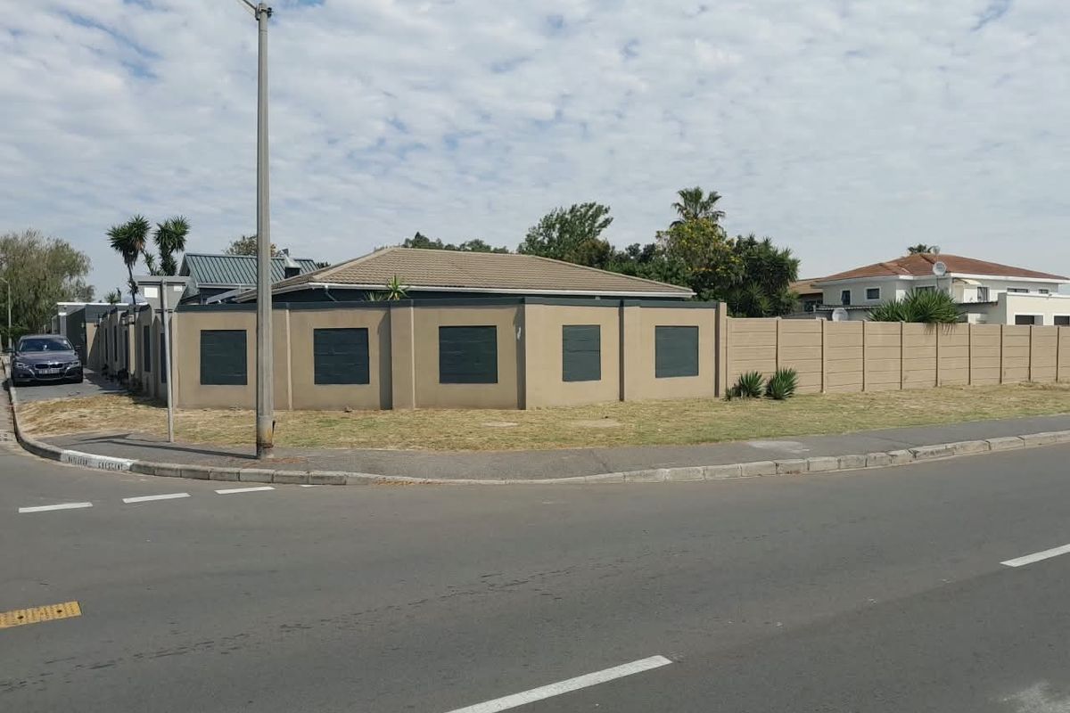 Street view of the property showing the perimeter wall, tiled roof, and surrounding pavement area.