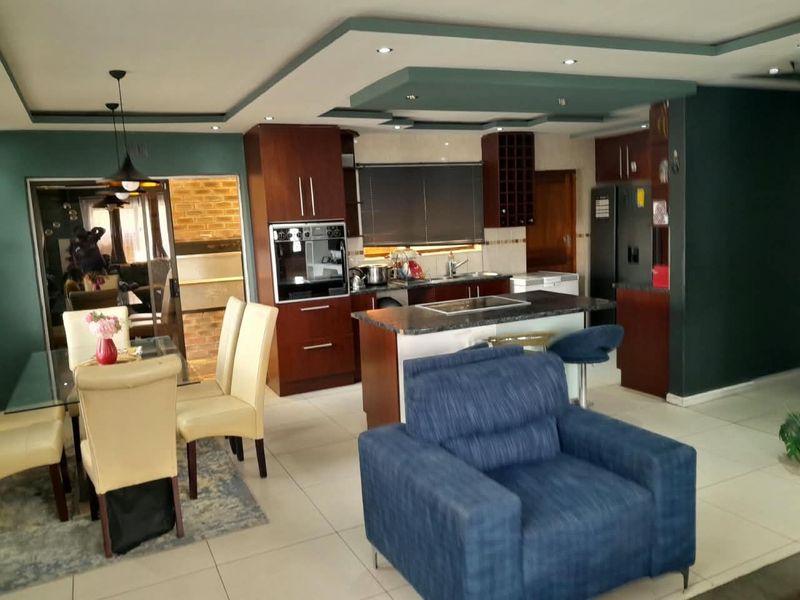 Open plan kitchen and dining area featuring dark wood cabinetry, a central kitchen island, and modern recessed ceiling lighting.