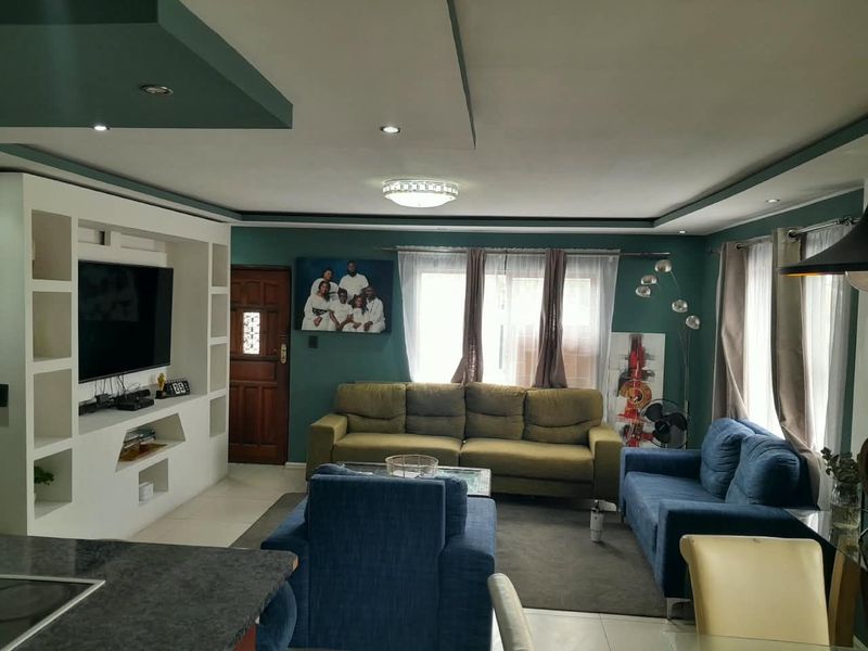 Open plan living area featuring a custom built-in media wall, recessed ceiling lighting, and tiled flooring, creating a functional and cohesive living space.