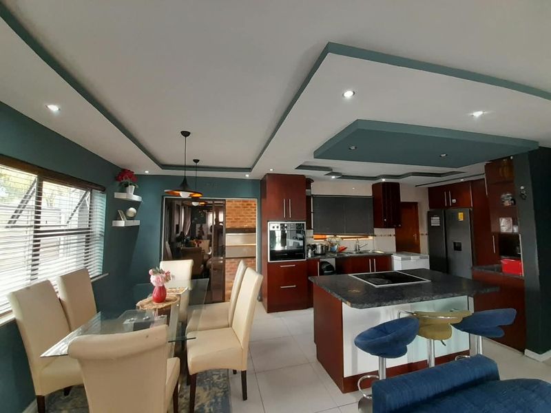 Spacious open-plan kitchen and dining area featuring a central island with hob, built-in oven, modern cabinetry, and a stylish recessed ceiling design.
