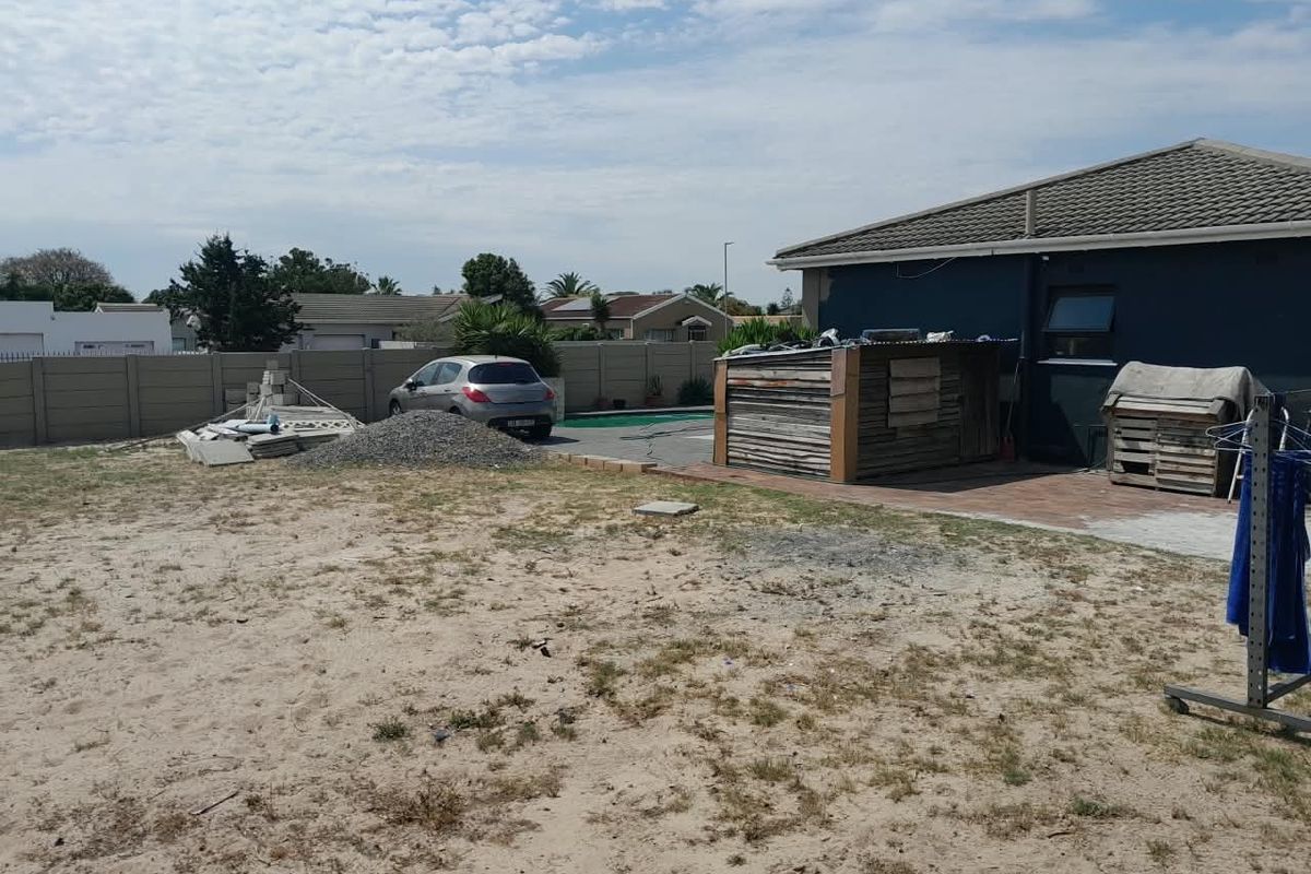 Rear exterior view of the property featuring a swimming pool, paved patio, and a large unlandscaped yard area requiring maintenance and development.