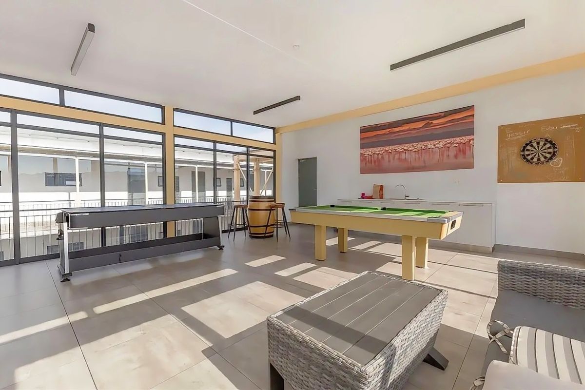 Spacious entertainment area featuring large glass sliding doors, tiled flooring, and a built-in kitchenette with a sink.