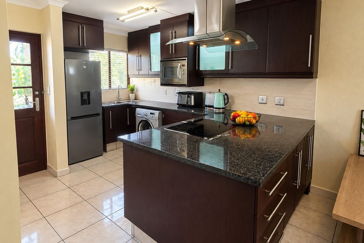 Modern kitchen featuring dark wood cabinetry, granite countertops, stainless steel appliances, and tiled flooring with direct access to the exterior.