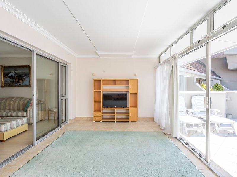 Bright and airy living room featuring large sliding glass doors that provide ample natural light and seamless access to the outdoor balcony area.