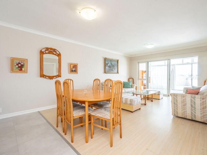 Spacious open-plan living and dining area featuring neutral walls, a mix of tiled and laminate flooring, and large sliding doors leading to a balcony.
