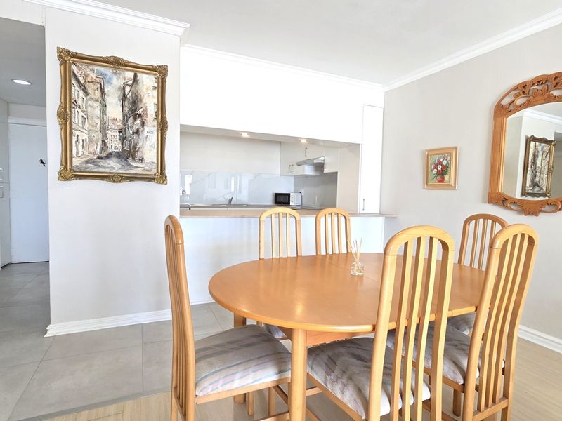Open plan dining area featuring a seamless transition to a functional kitchen with built-in cabinetry and modern finishes.