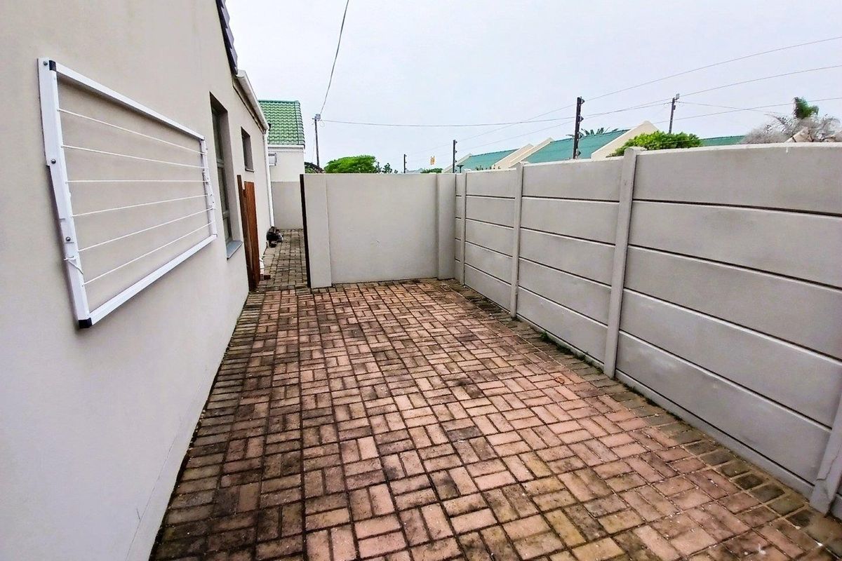 A private rear courtyard featuring paved flooring, a precast concrete boundary wall, and a wall-mounted clothesline.