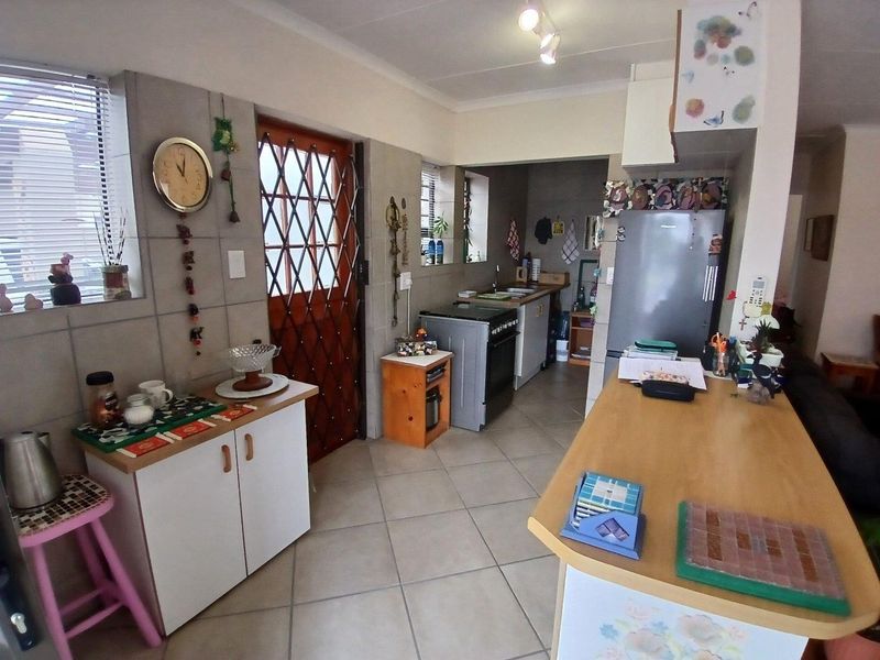 Functional kitchen featuring tiled flooring, built-in cabinetry, a freestanding stove with extractor fan, and a double sink with direct exterior access.